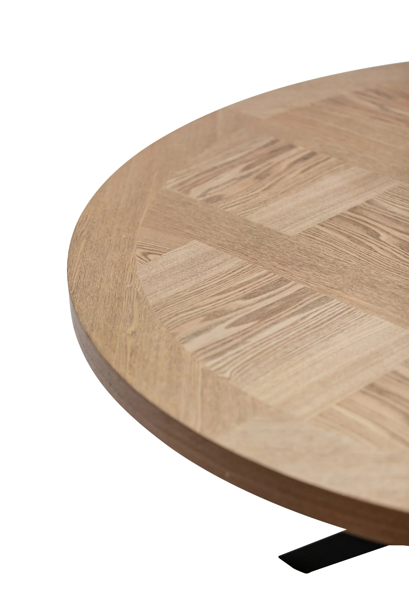 Closeup of round wooden dining table with parquet top and light natural wood finish