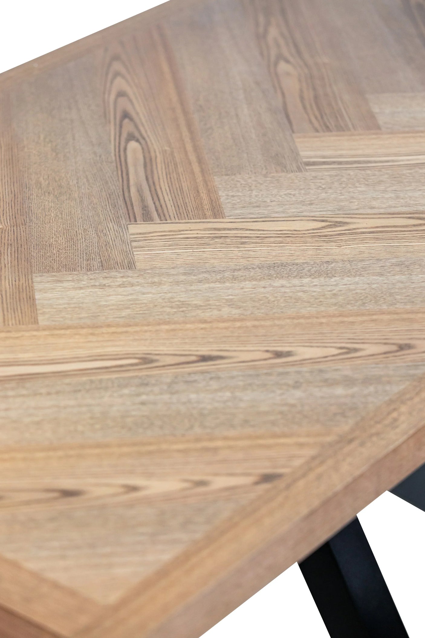 Closeup of wooden dining table with herringbone pattern and black metal legs