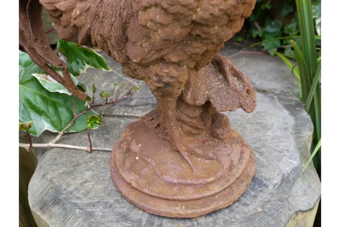 Detailed close-up of a cast iron rooster garden ornament with rustic finish on wooden surface