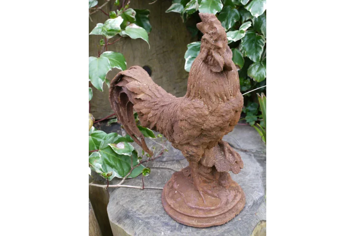 cast iron rooster ornament on stone base in garden setting