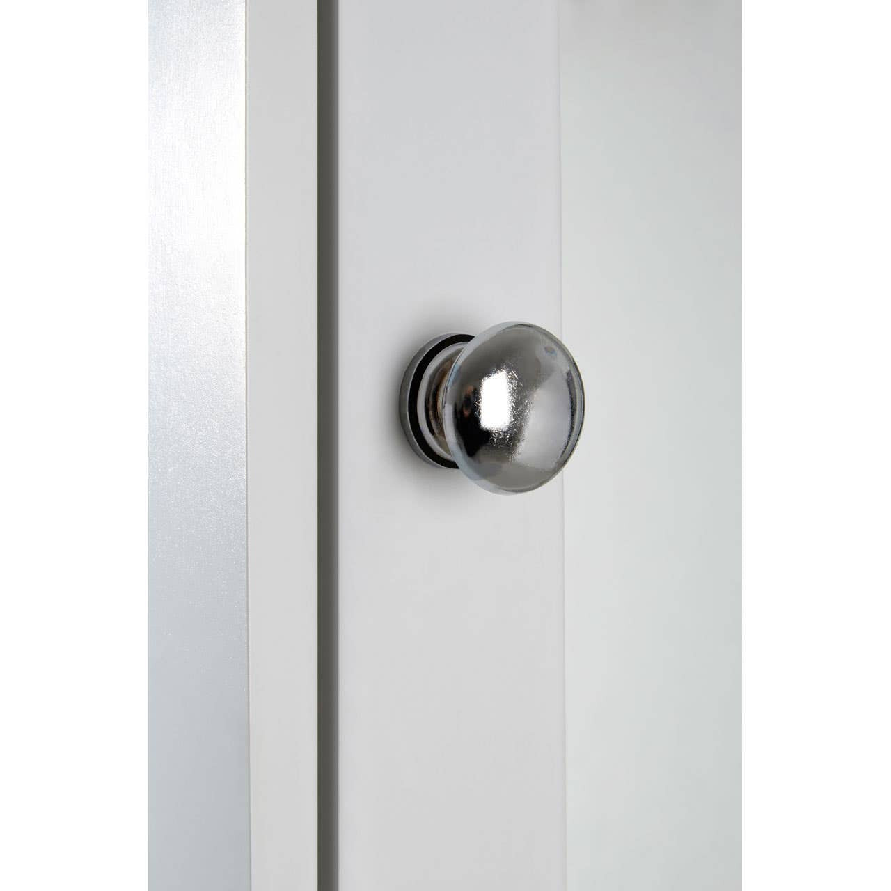Close-up view of a sleek, modern cabinet featuring a mirrored surface and a round, metallic knob. The cabinet has a clean, minimalist design with a light-colored finish
