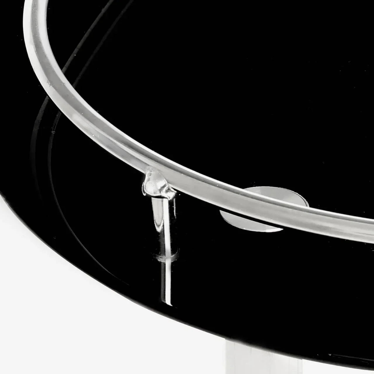 Close-up of black glass side table top with chrome trim and clear support bar