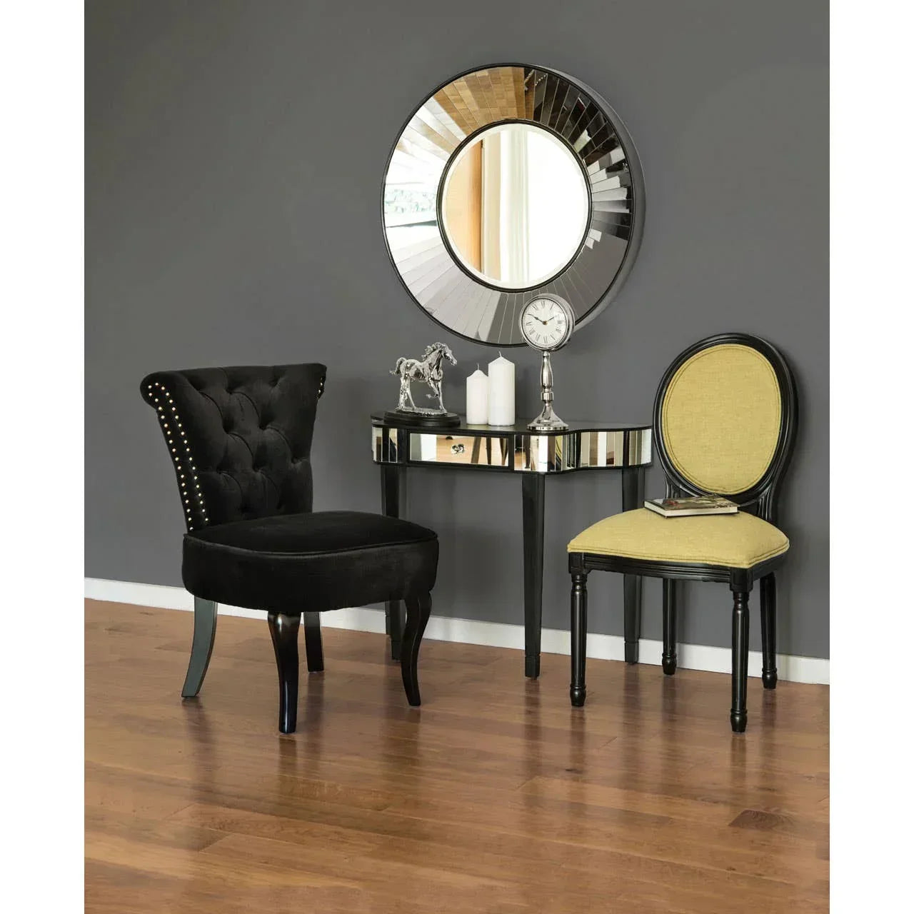Mirrored console table with decorative mirror, black velvet chair, and yellow accent chair