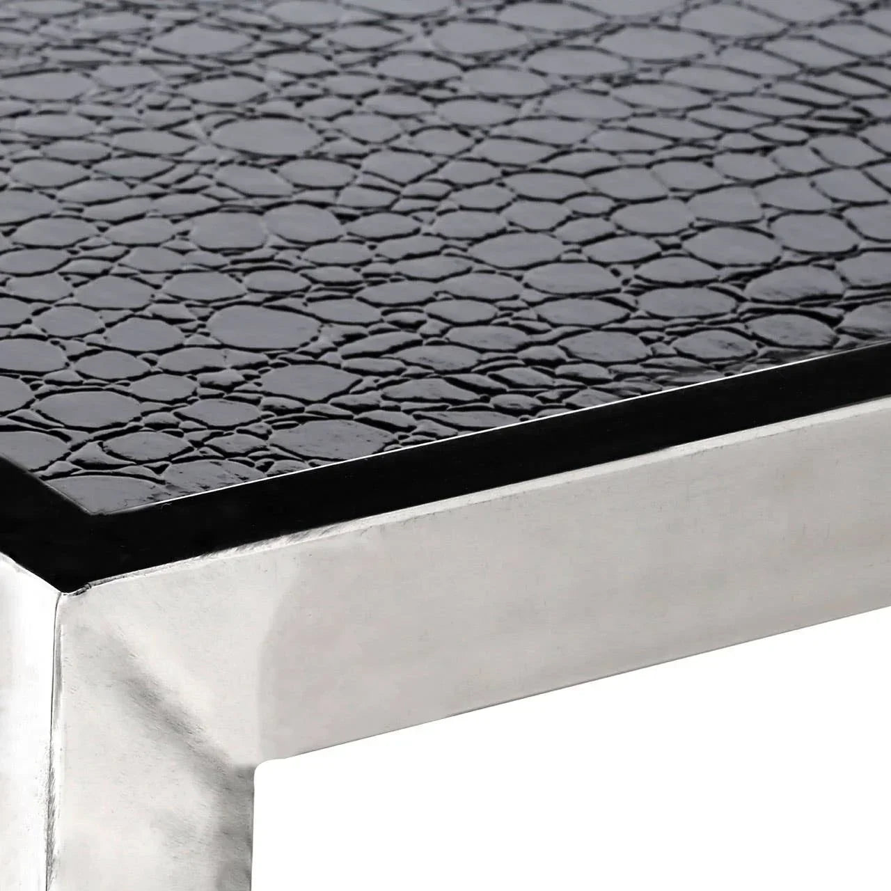 Close-up of black textured coffee table top with silver metal frame corner