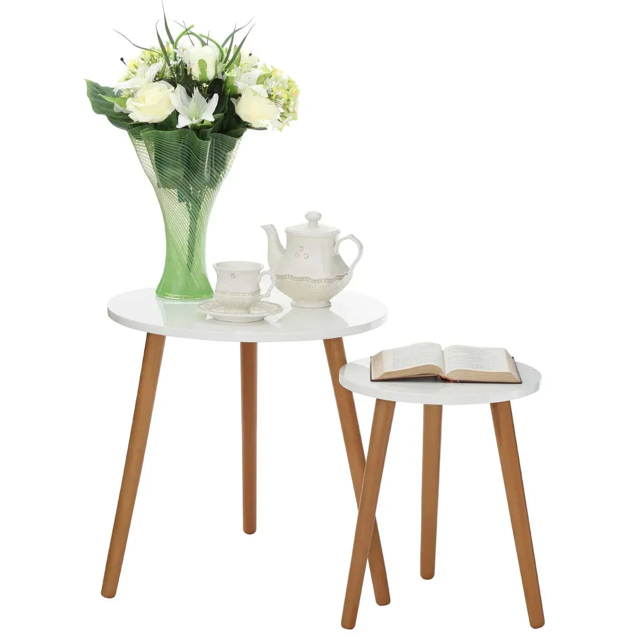Set of white nesting side tables with wooden legs, holding vase, teapot set and open book