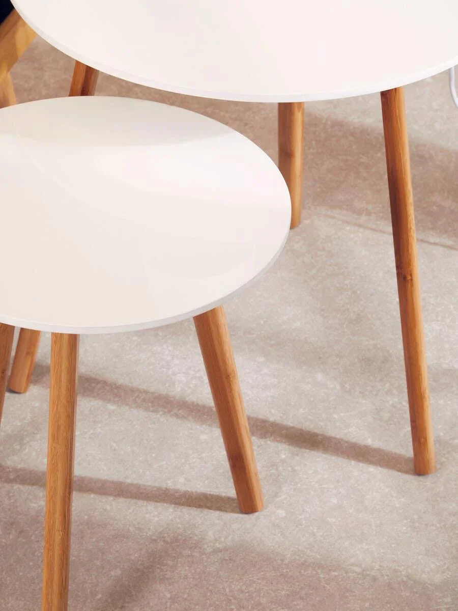 White round nesting tables with wooden legs on light tiled floor