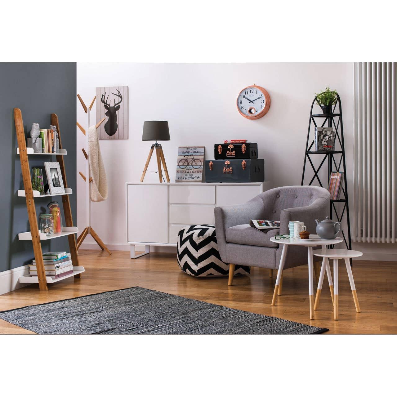 Modern living room with grey armchair, white side table, geometric pouffe and wooden shelving