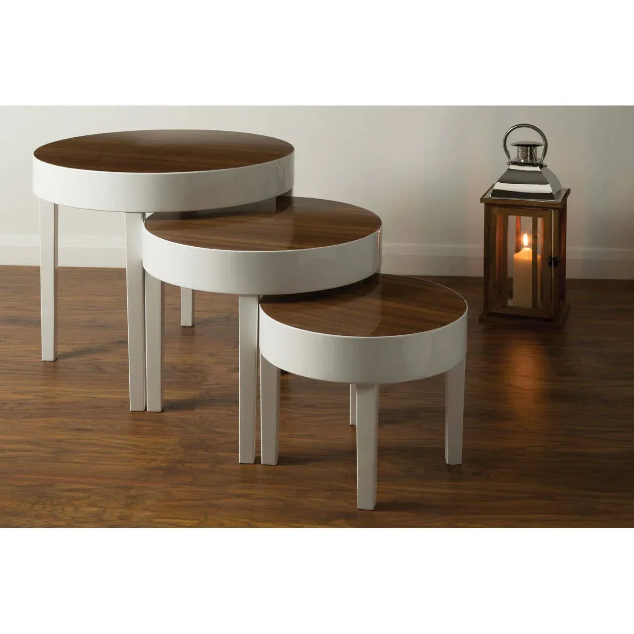 Set of three round nesting tables with wood tops and white legs on wooden floor