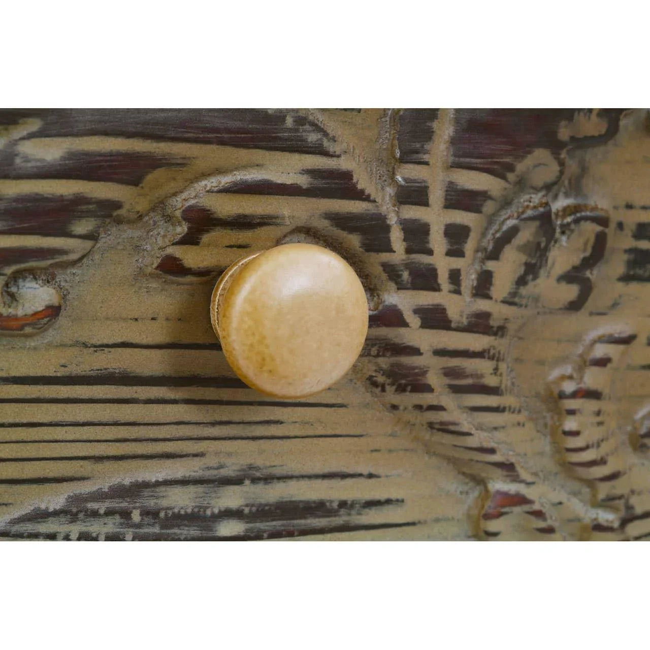 Close up of wooden drawer knob on distressed carved furniture surface