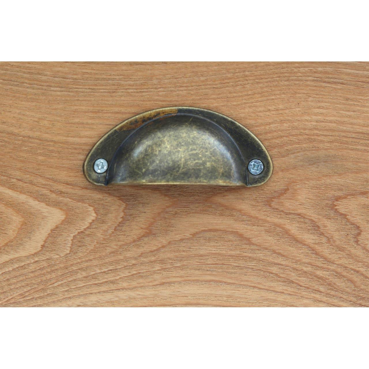 Antique brass cup drawer handle on light oak wood furniture surface