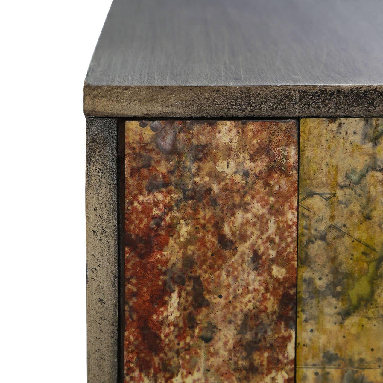 Close-up of textured metal and wood cabinet corner with rustic, multicolor finish