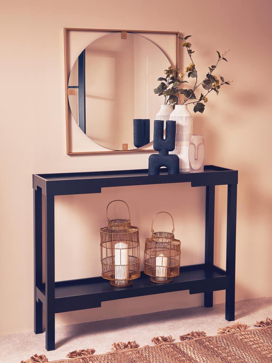 Black hallway console table with decorative vases, mirror, and two lanterns on lower shelf
