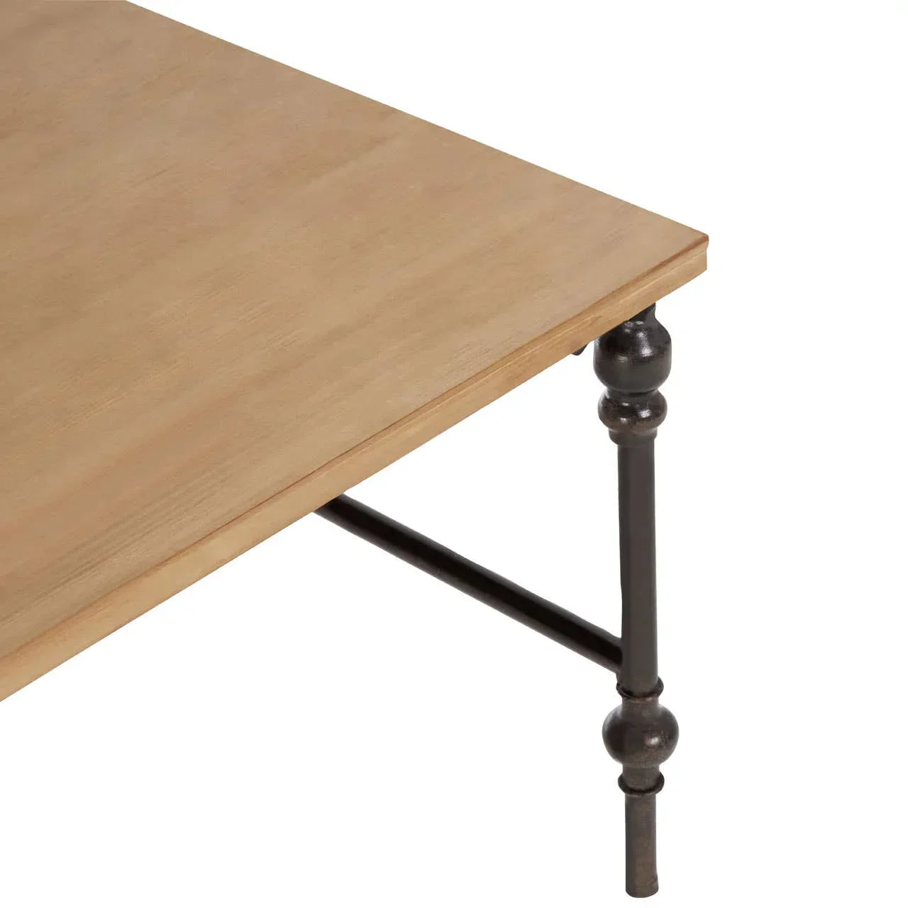 Closeup of wood dining table top with black metal leg and crossbar