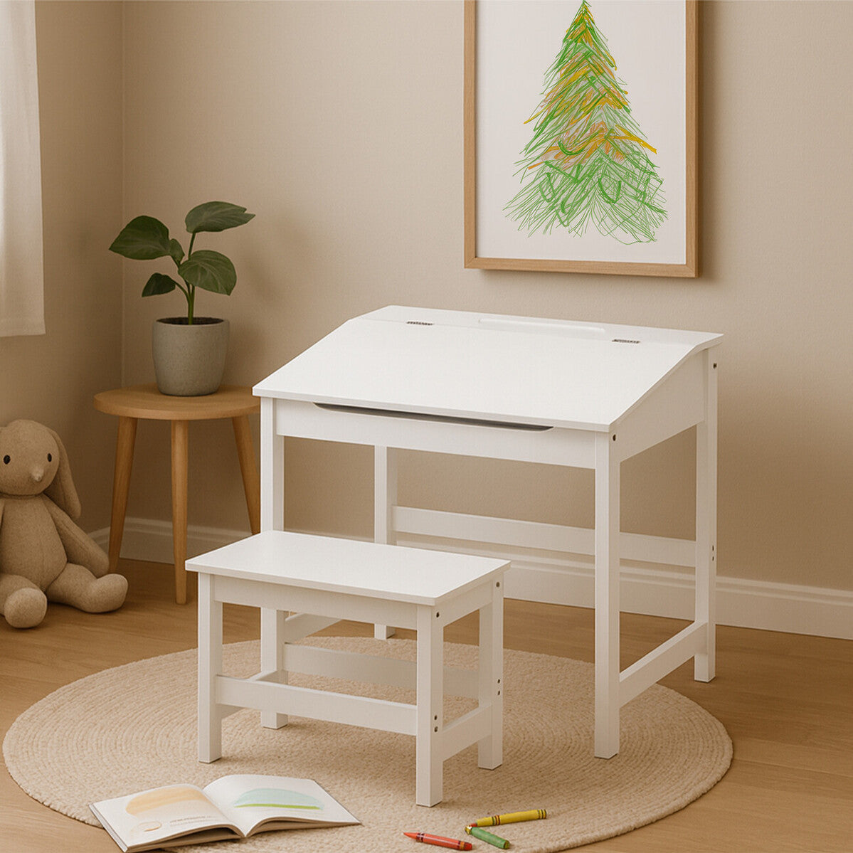 A white children's desk with a slanted top and a matching stool, placed on a circular rug in a cozy room. A framed artwork featuring a green tree is hung on the wall, and a small plant sits on a side table next to the desk. A stuffed animal is visible on the floor