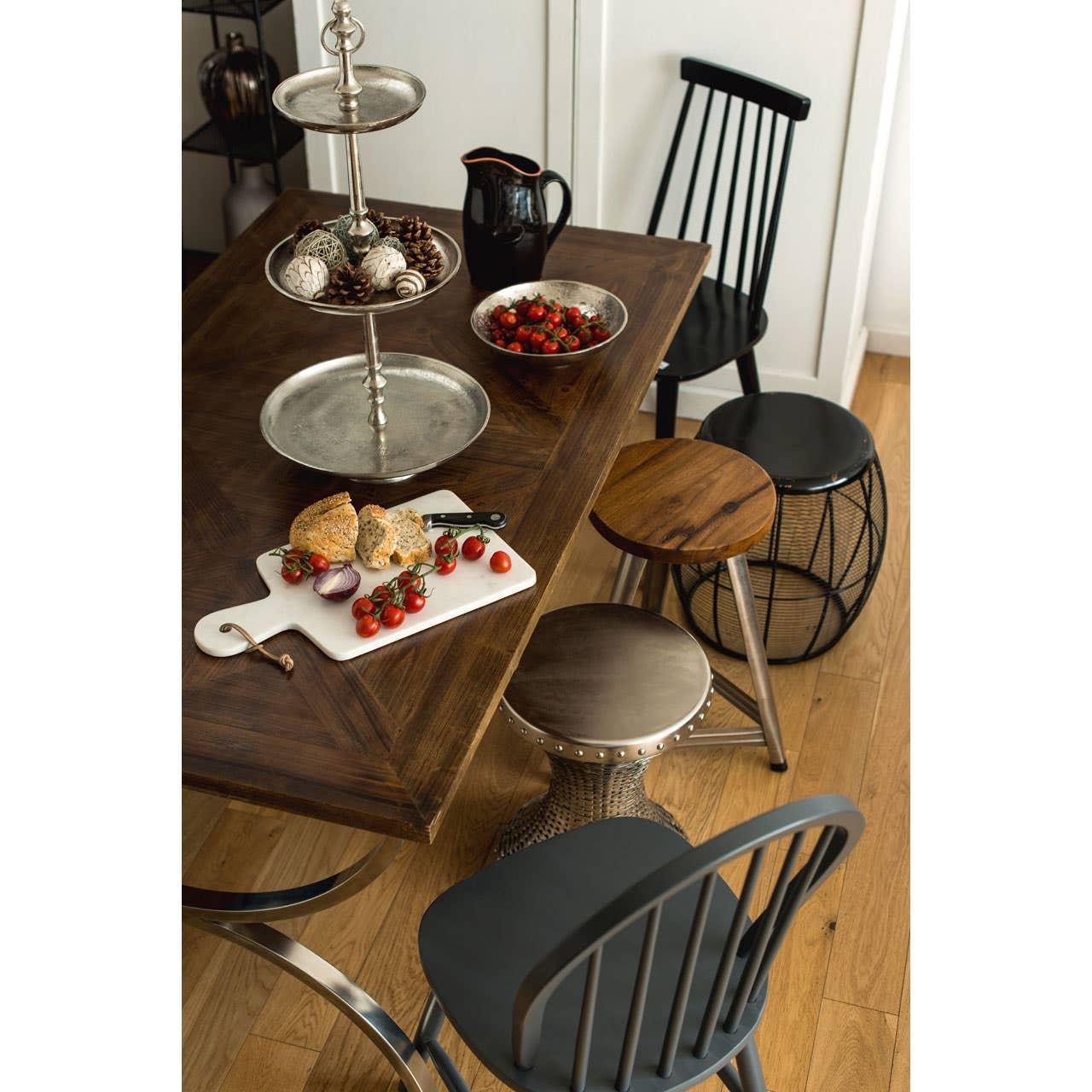 Wood dining table with metal tiered stand, cutting board, mixed stools and black chair