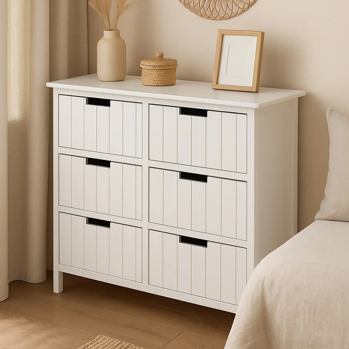White wooden chest of drawers with six panels beside a beige bed in a modern bedroom