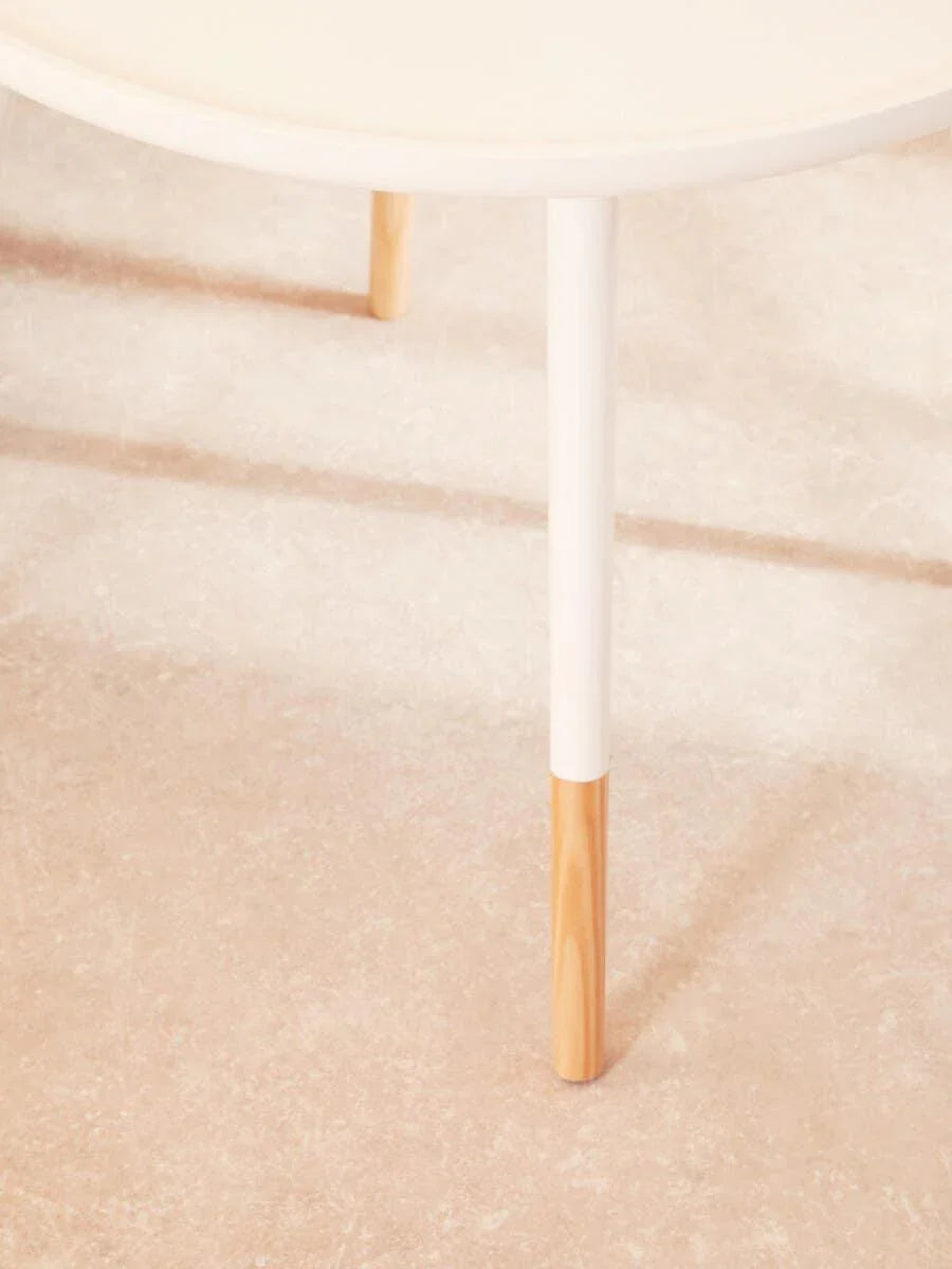 Round white coffee table with wooden dipped legs on light textured floor