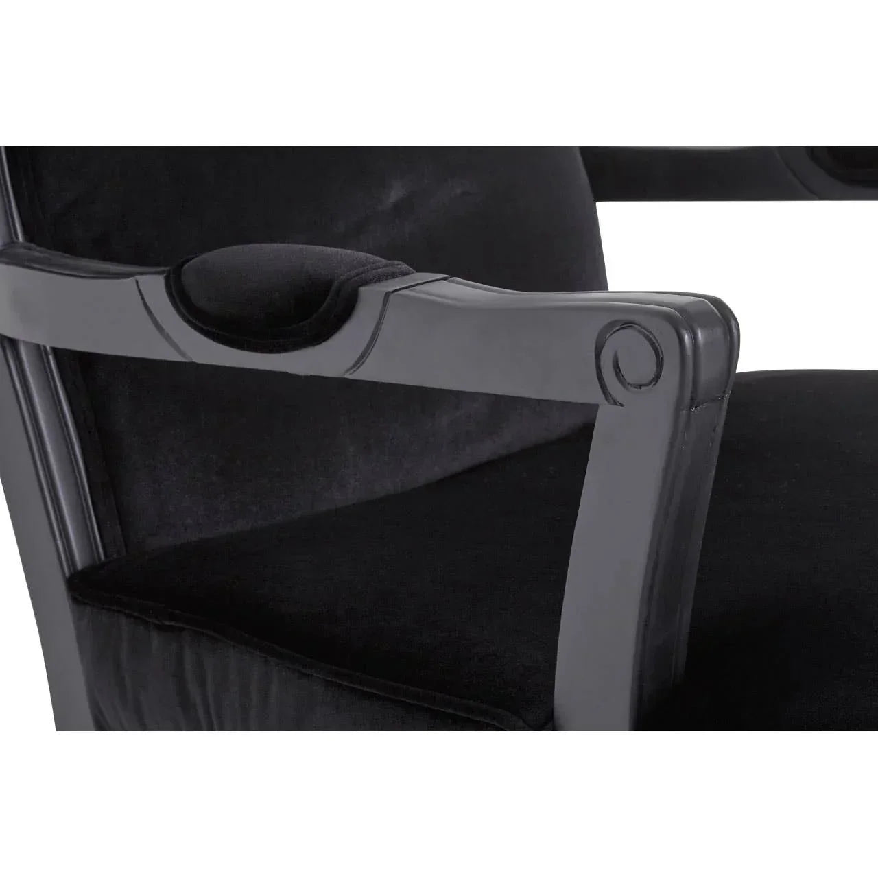 Black velvet armchair seat and armrest with carved wood detailing closeup