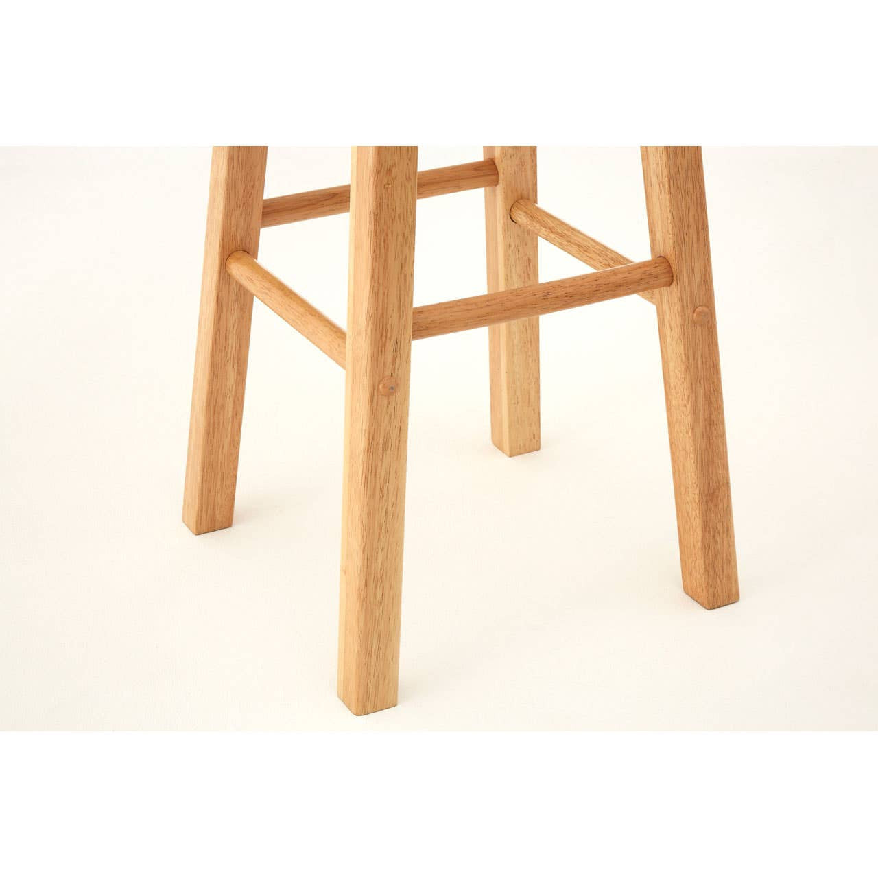Natural tropical hevea wood tall bar stool featuring a simple design with four sturdy legs and a crossbar for added support. The wood has a light, warm finish that highlights its natural grain