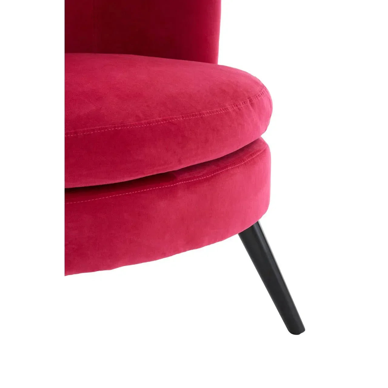 Close-up of pink velvet accent chair seat and black angled leg
