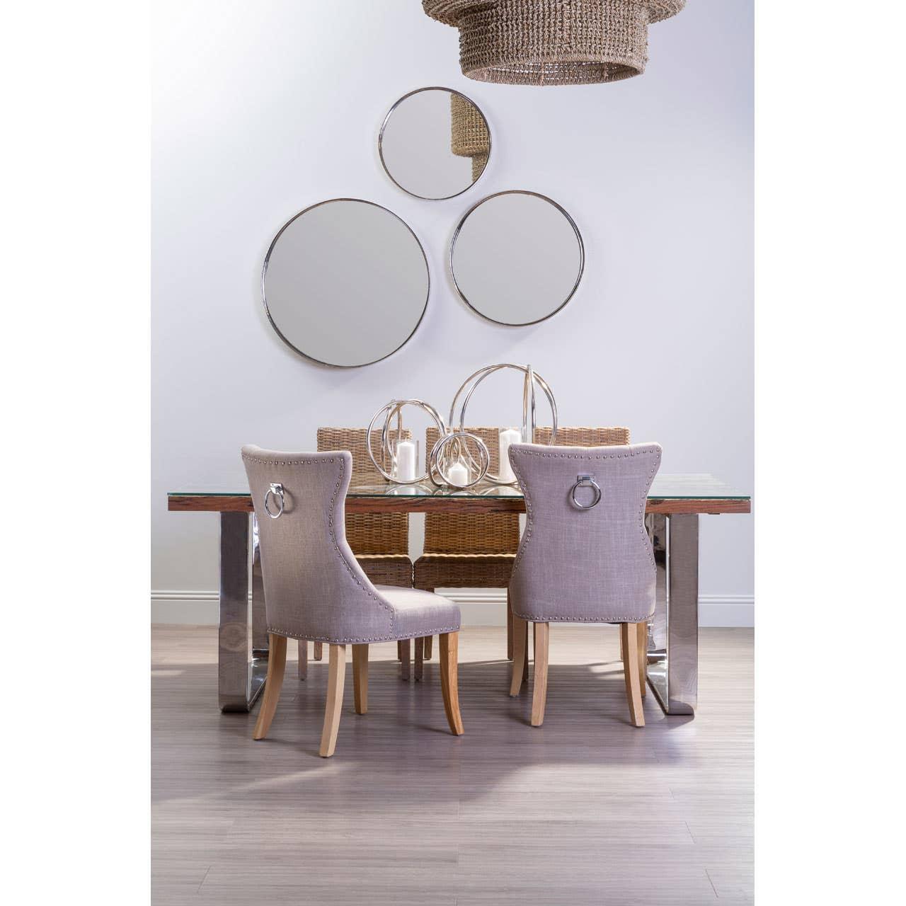 Glass dining table with chrome legs, beige upholstered chairs and woven accents in modern room