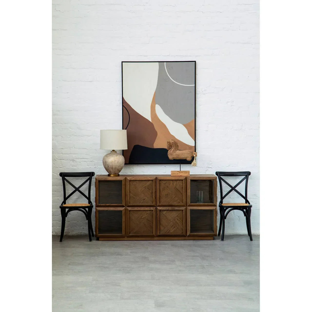 Wooden sideboard with geometric doors, two black dining chairs, table lamp, abstract wall art