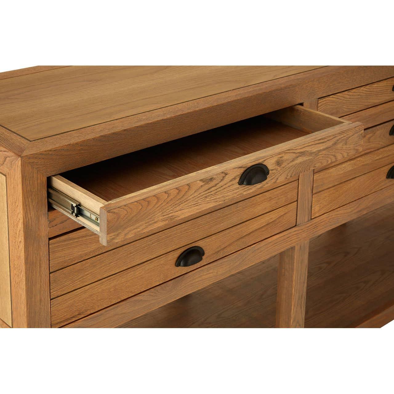 Oak sideboard with open drawer and black handles, close-up on wood grain detail