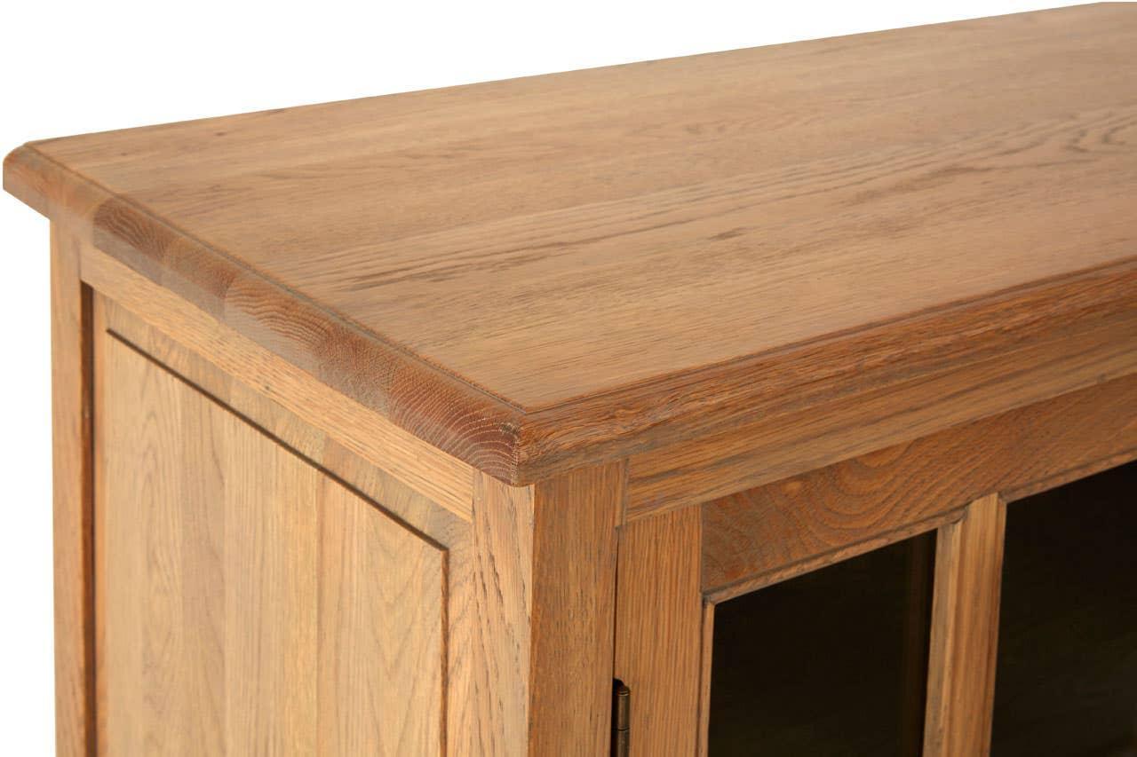 Corner detail of wooden sideboard cabinet with natural oak finish and glass panel door
