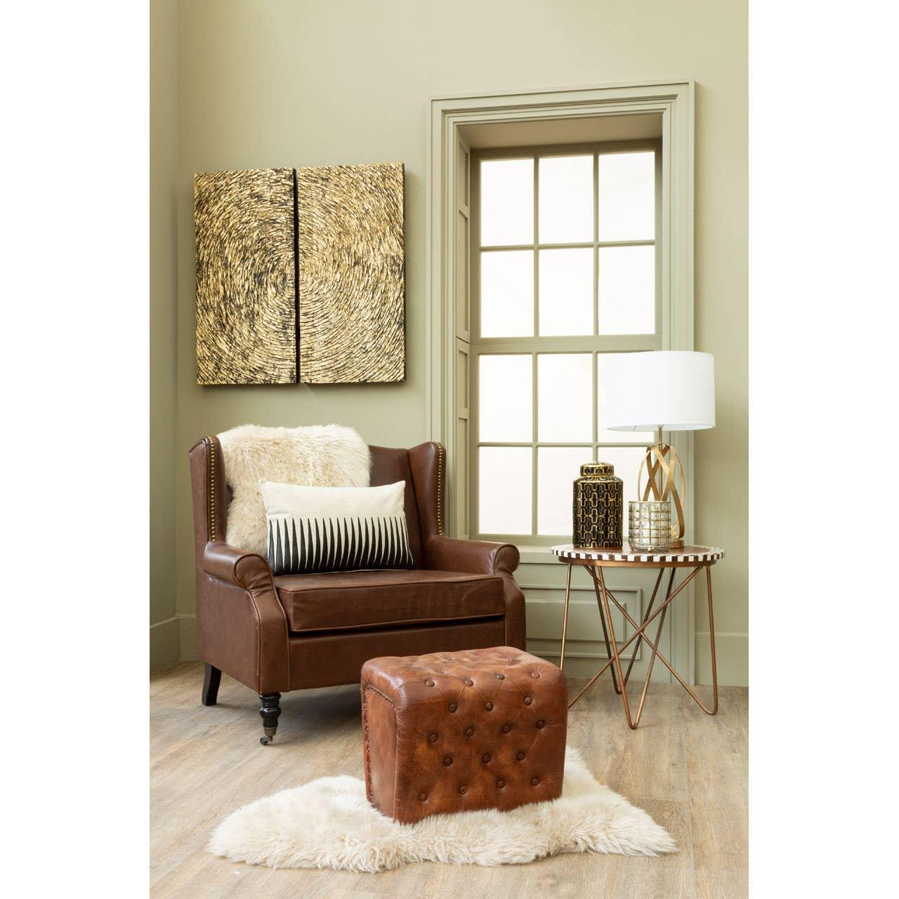Brown leather armchair and footstool with neutral cushion, side table and decorative lamp