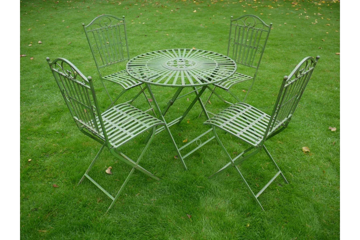 Green metal garden furniture set with round table and four matching chairs on grass