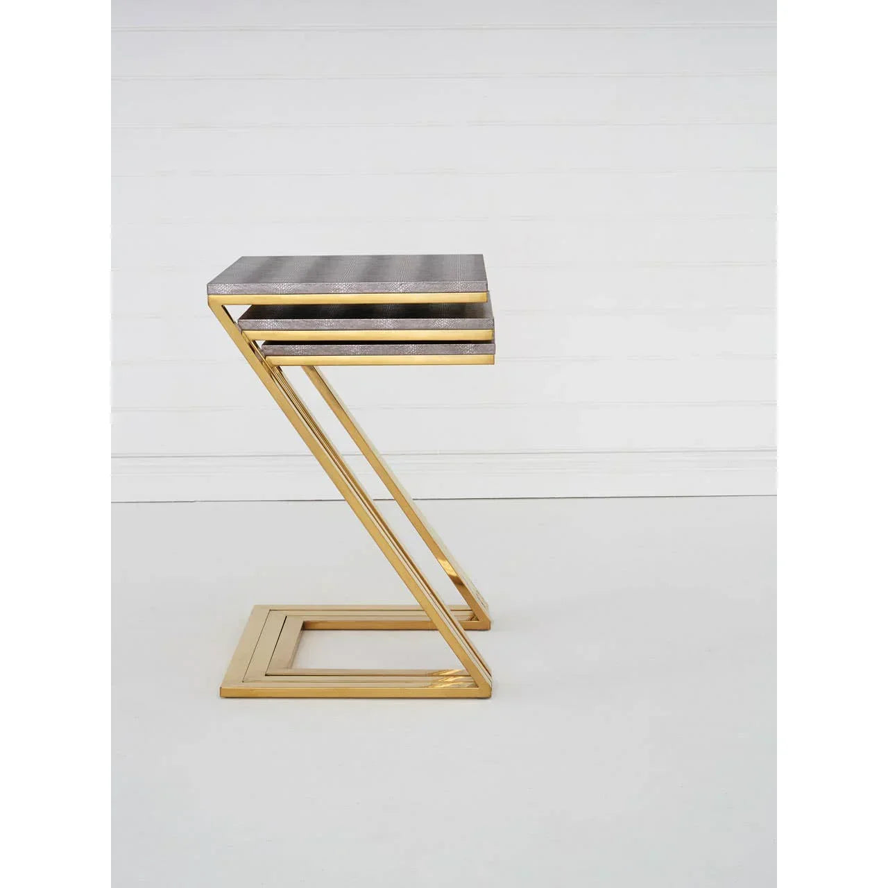 Modern side table with gold metal Z-frame and textured grey top on white background