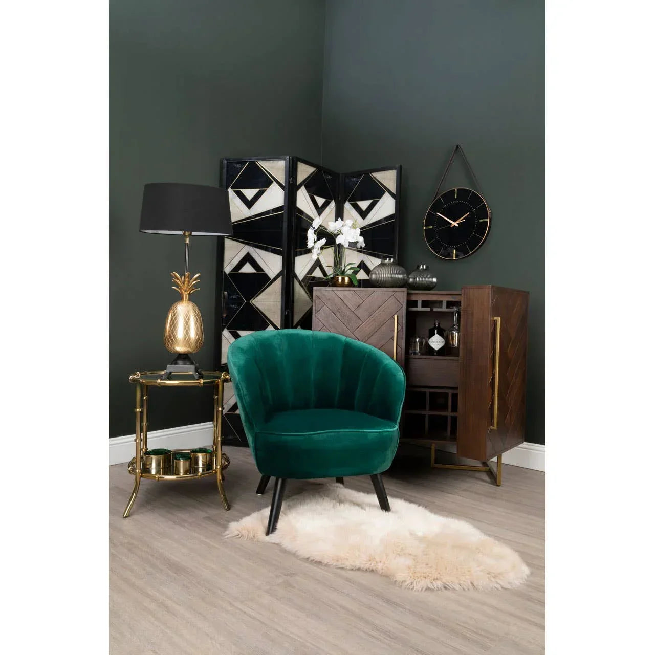 Green velvet accent chair with black legs in modern living room setup with gold side table