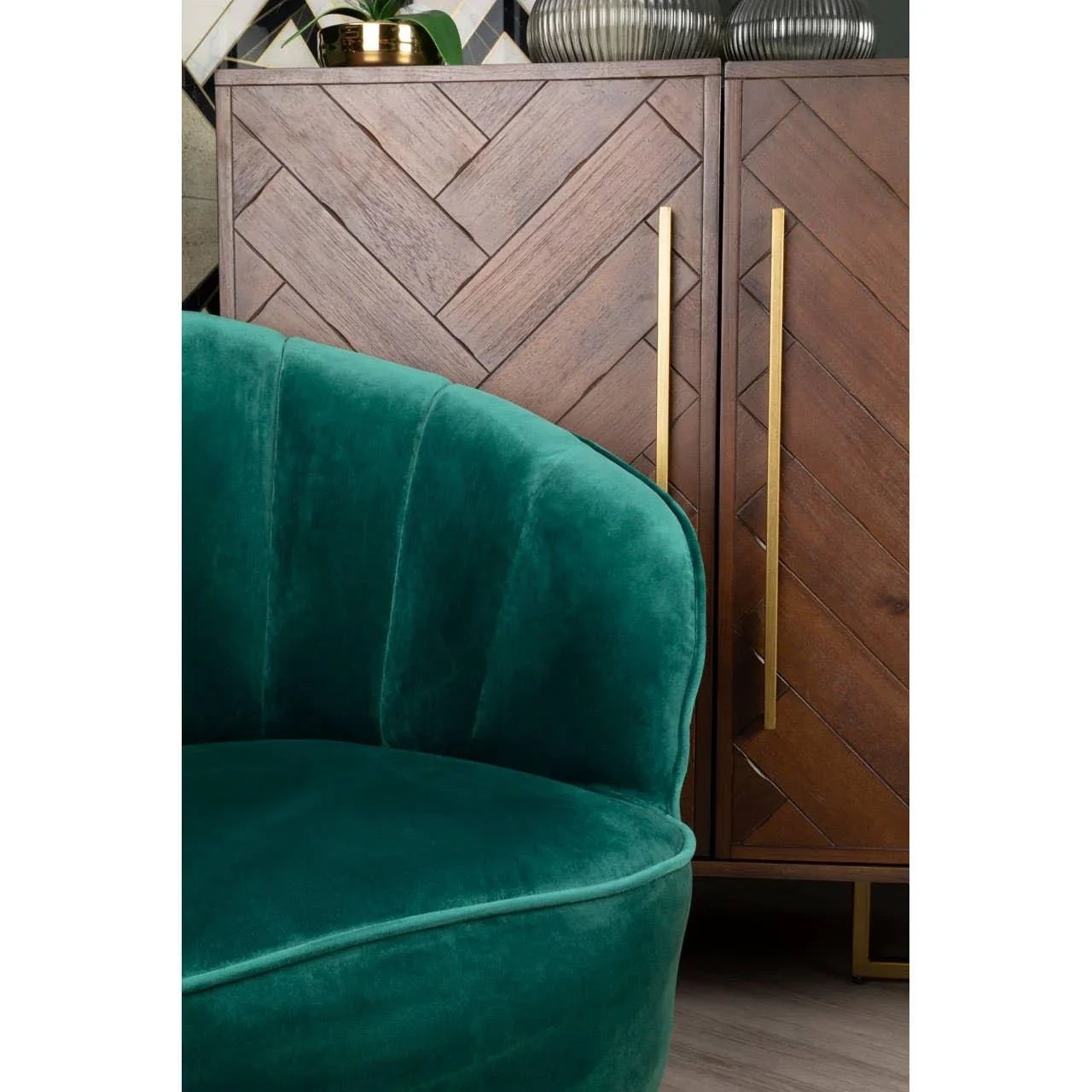Green velvet accent chair in front of geometric wood sideboard with gold handles