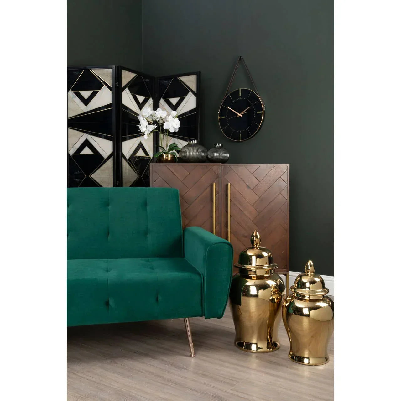 Green velvet sofa and gold ceramic jars in modern living room with wood cabinet and wall clock