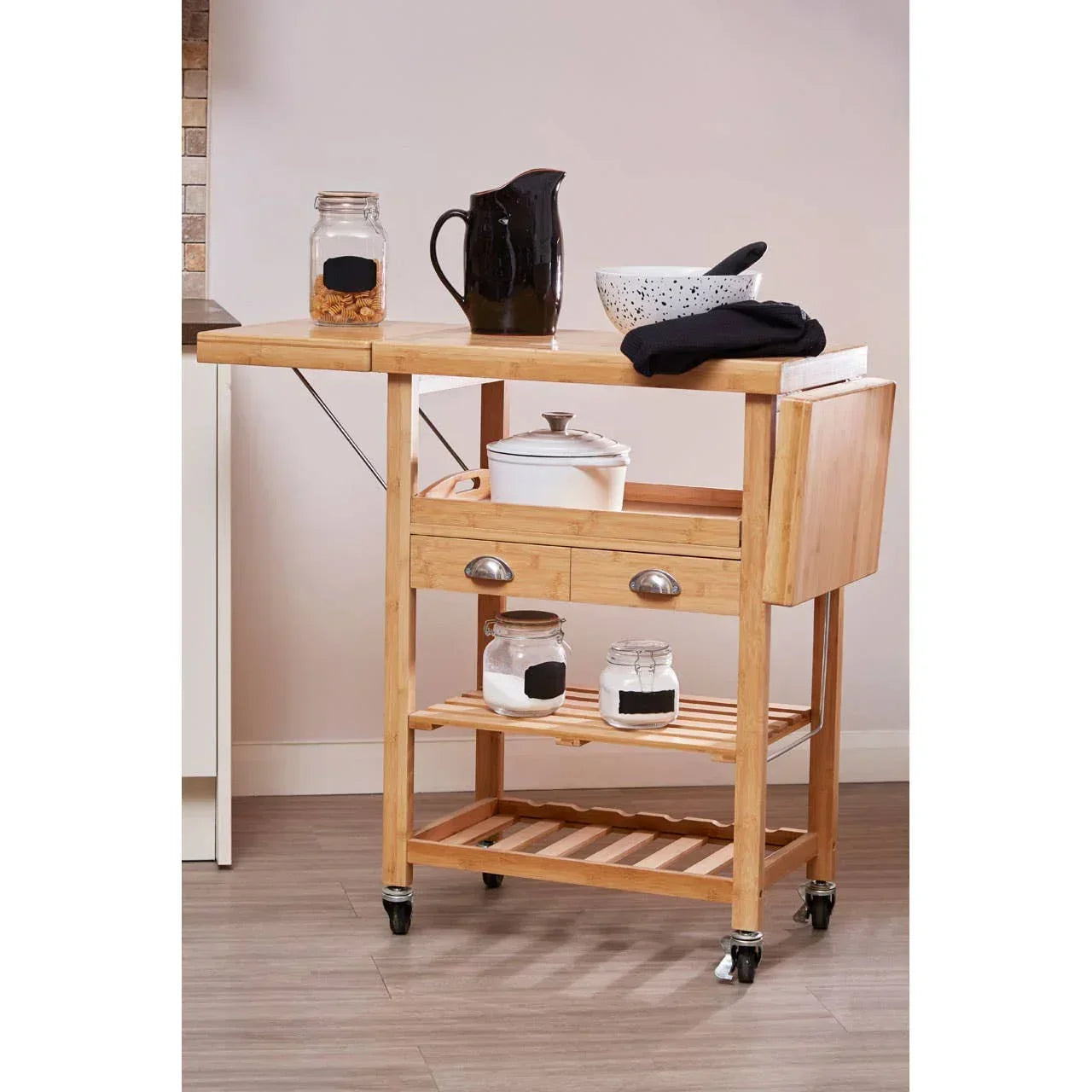 Wooden kitchen trolley cart with drawers, shelves, storage jars, and black pitcher