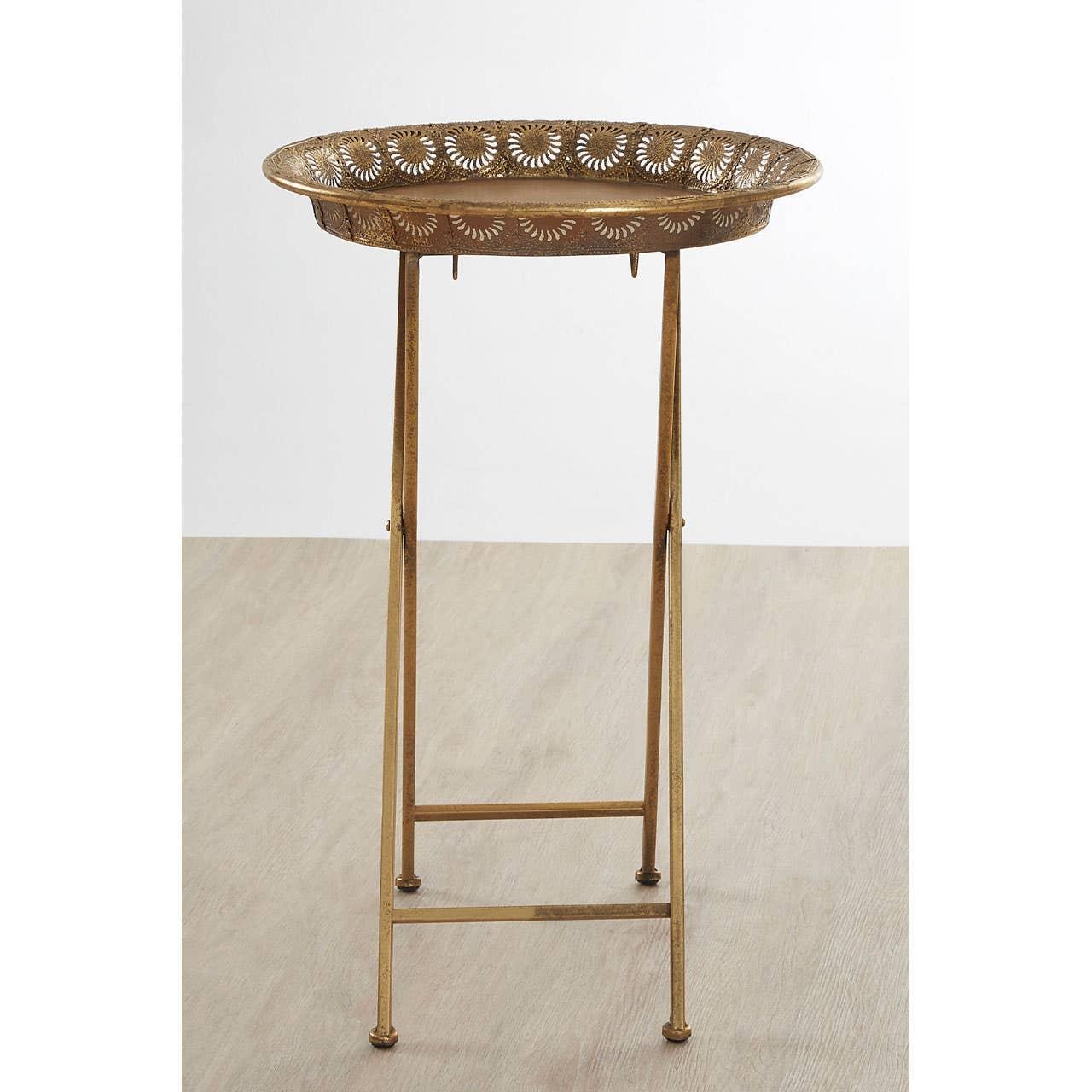 Gold metal side table with intricate cut-out tray top and slim legs on wood floor