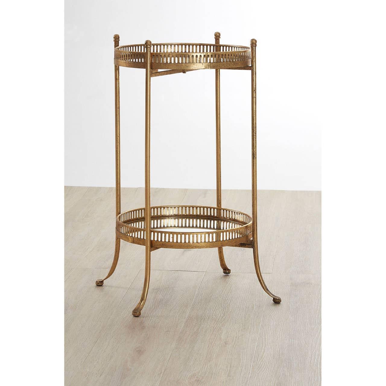 Gold metal side table with two circular trays and slim legs on wood floor