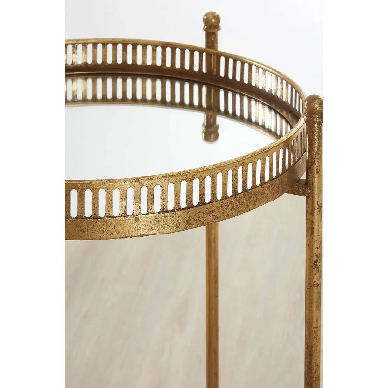Round glass side table with gold metal frame and decorative cutout trim, close-up view
