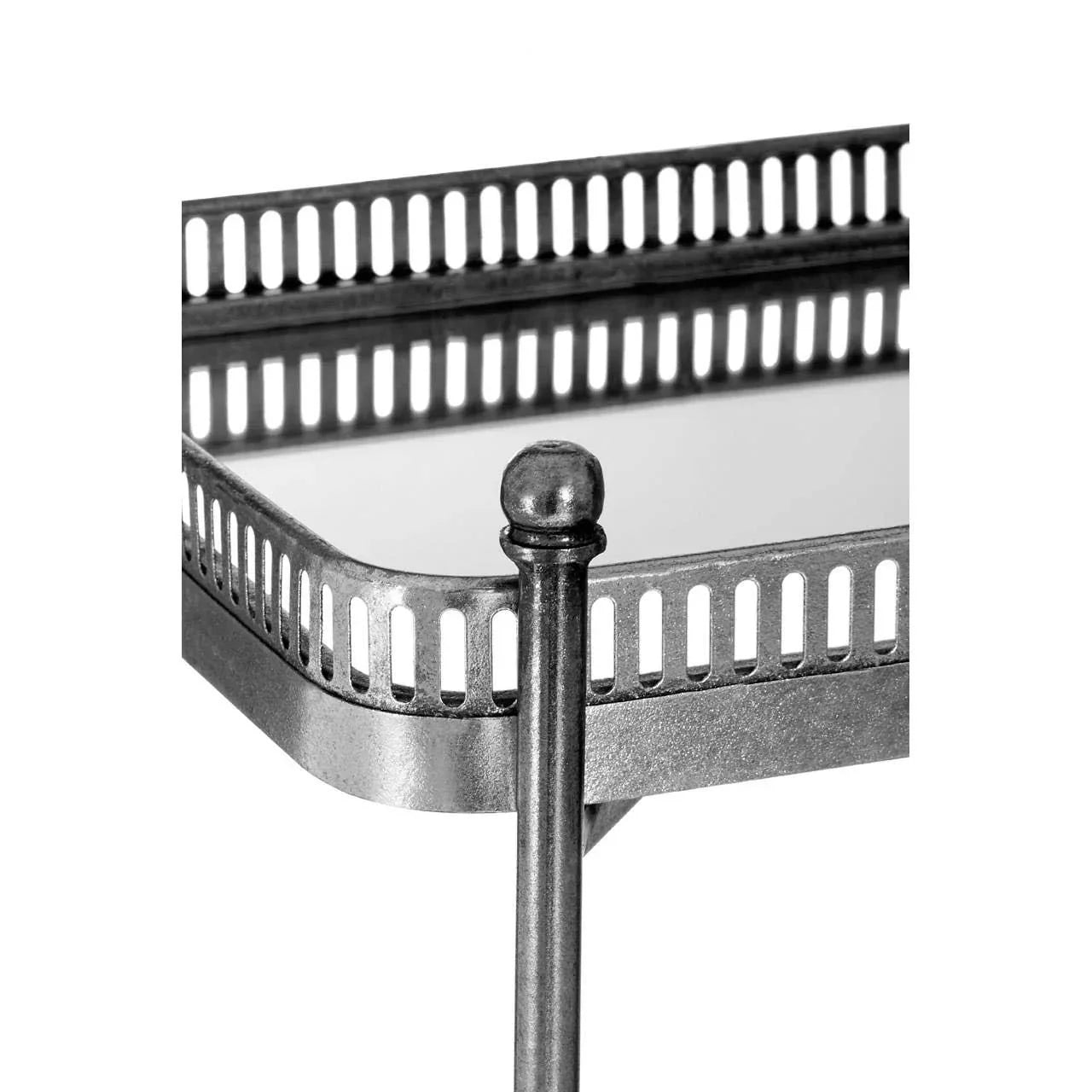 Close up of metal side table with mirrored top and decorative railing detail
