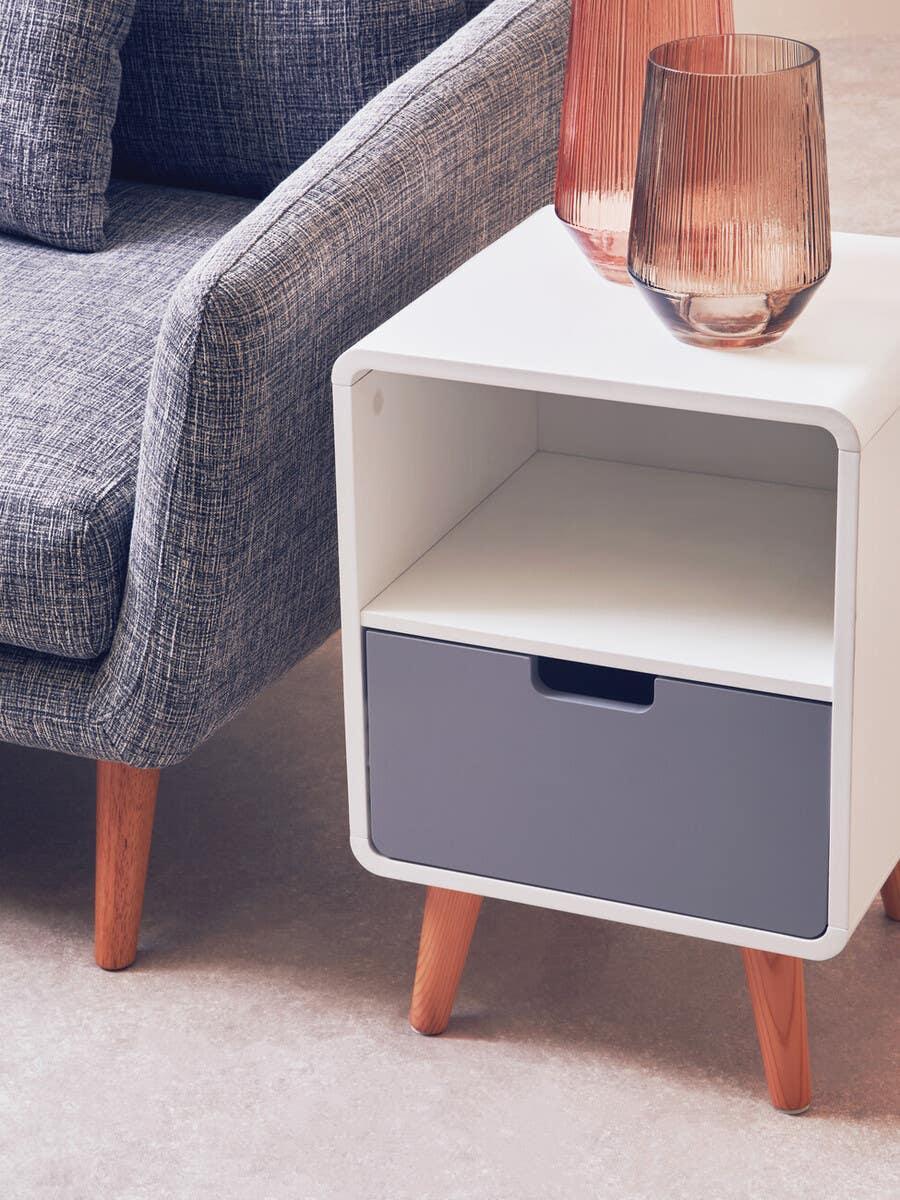Modern grey fabric sofa beside white and grey wooden side table with glass vases