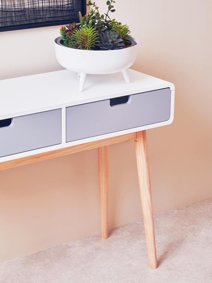 White and grey console table with light wood legs, topped with a modern succulent planter