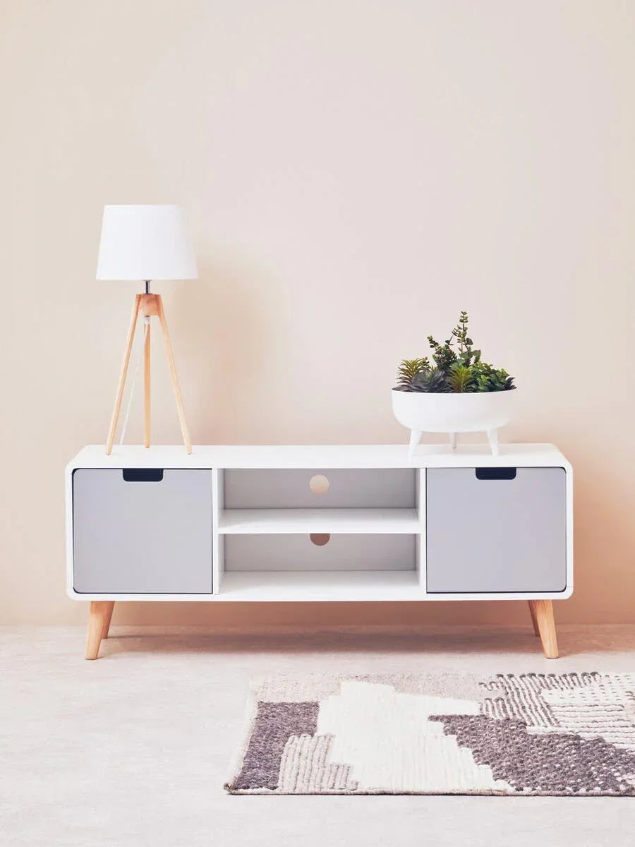 White and grey TV unit with wooden legs, lamp and plant on top, modern living room setting