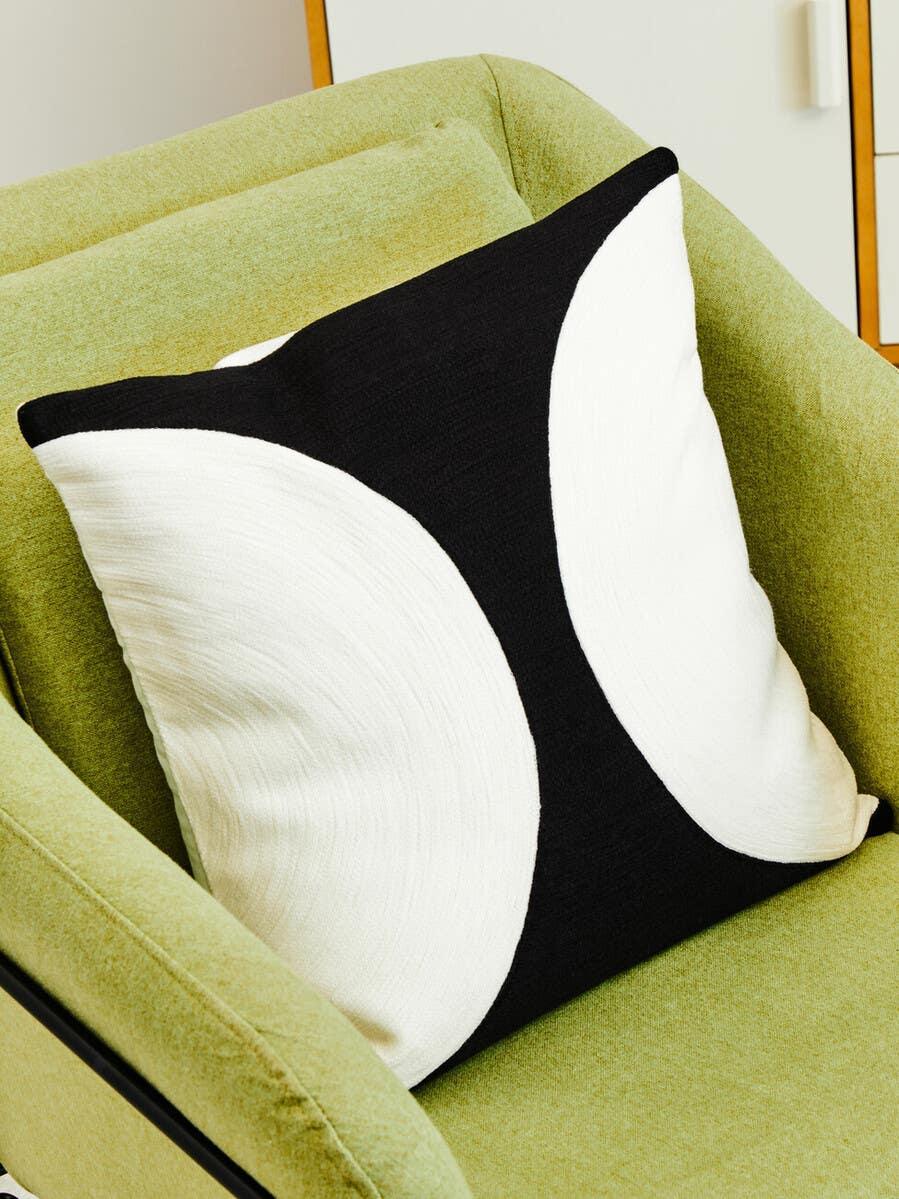 Black and white geometric cushion on light green fabric armchair