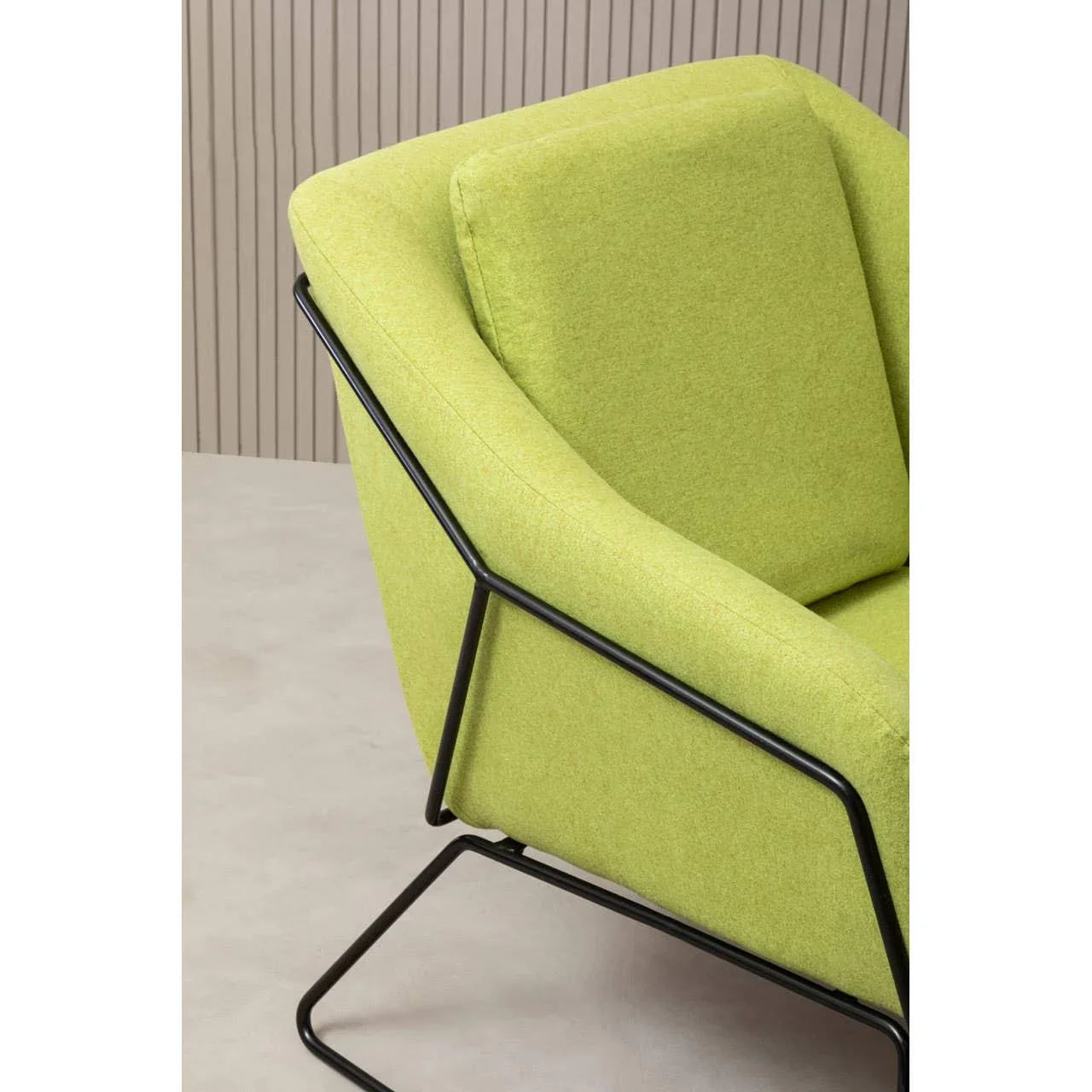 Green fabric armchair with black metal frame and angled backrest, side view