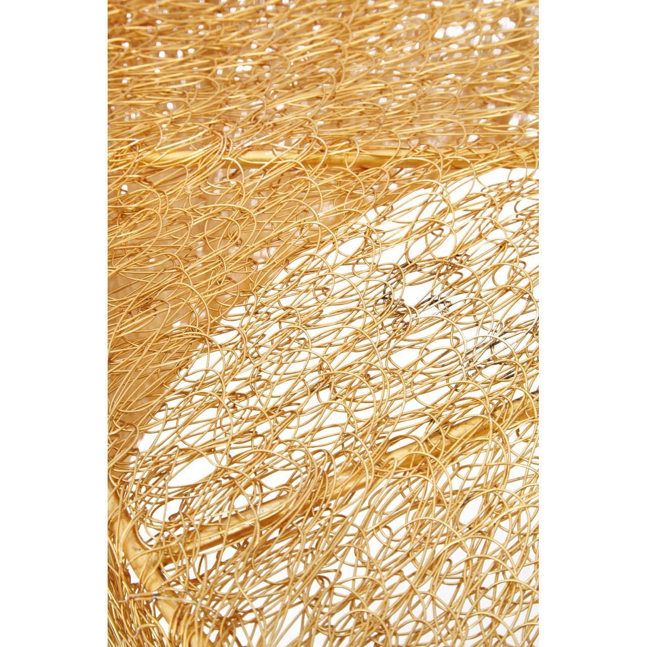 Gold wire metal table surface with intricate openwork design, close-up angle