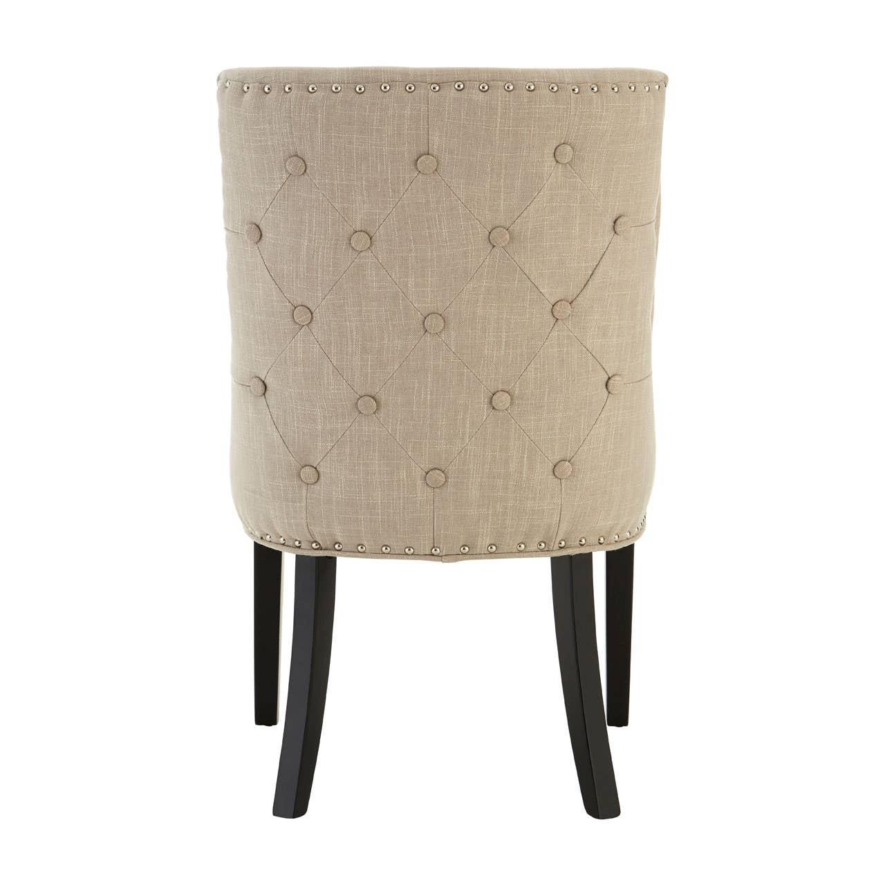 Beige upholstered dining chair with button tufted back and silver stud detailing, rear view
