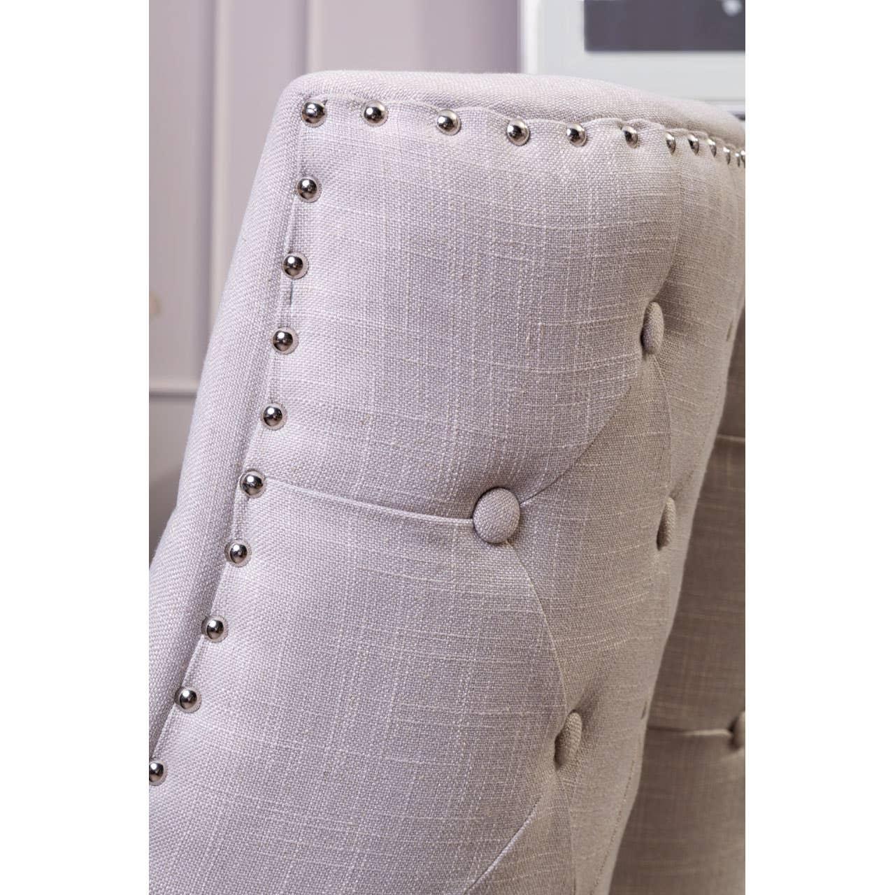 Light grey upholstered dining chair with button tufting and metal stud detailing, close view