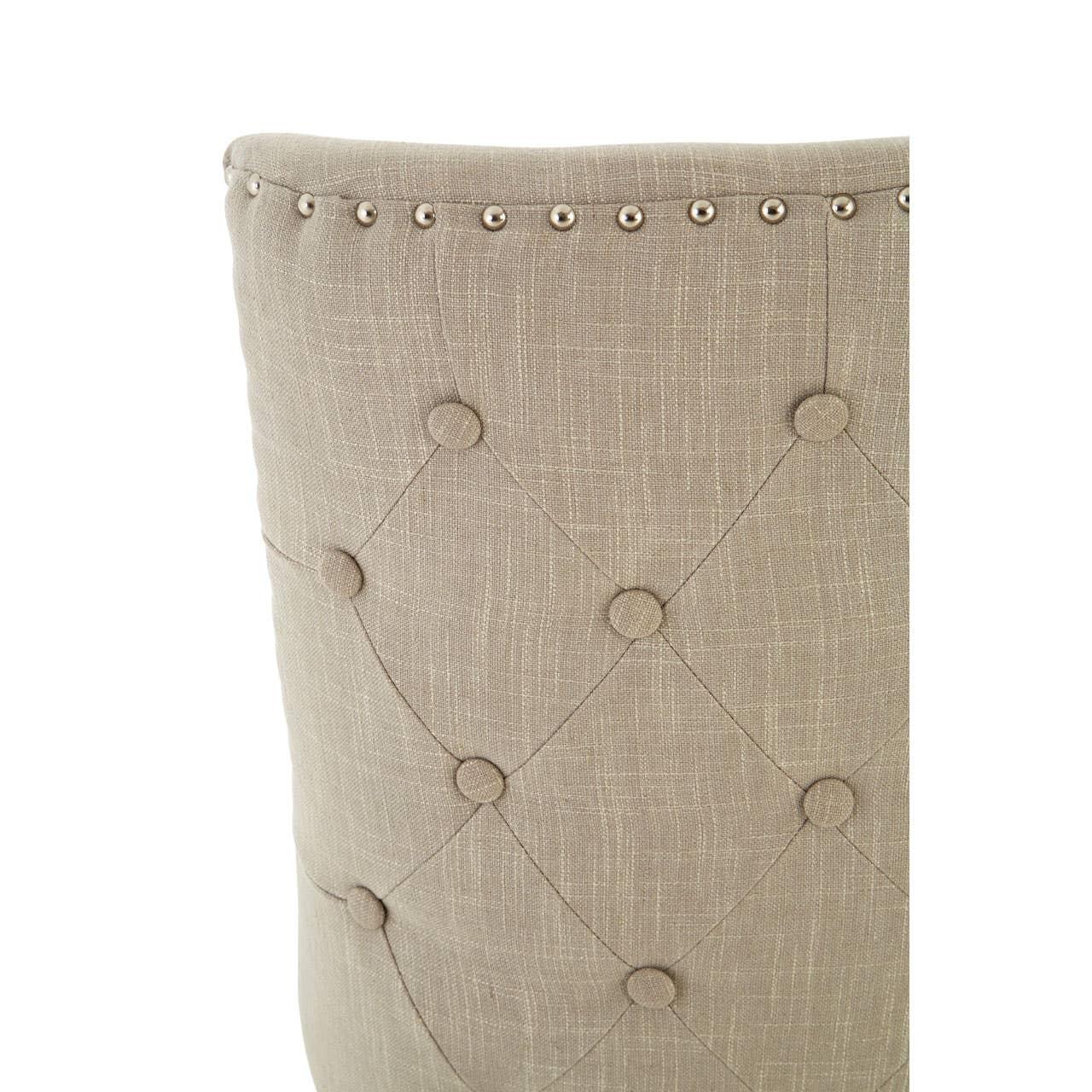 Beige upholstered dining chair back with button-tufting and metal stud trim detail