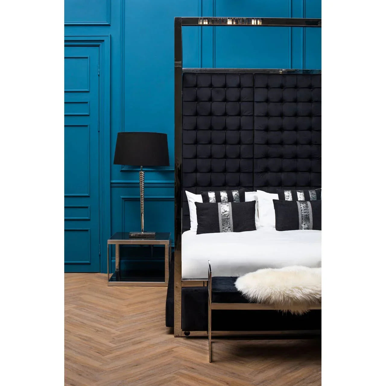 Black velvet four poster bed with chrome frame and matching bedside table in modern bedroom
