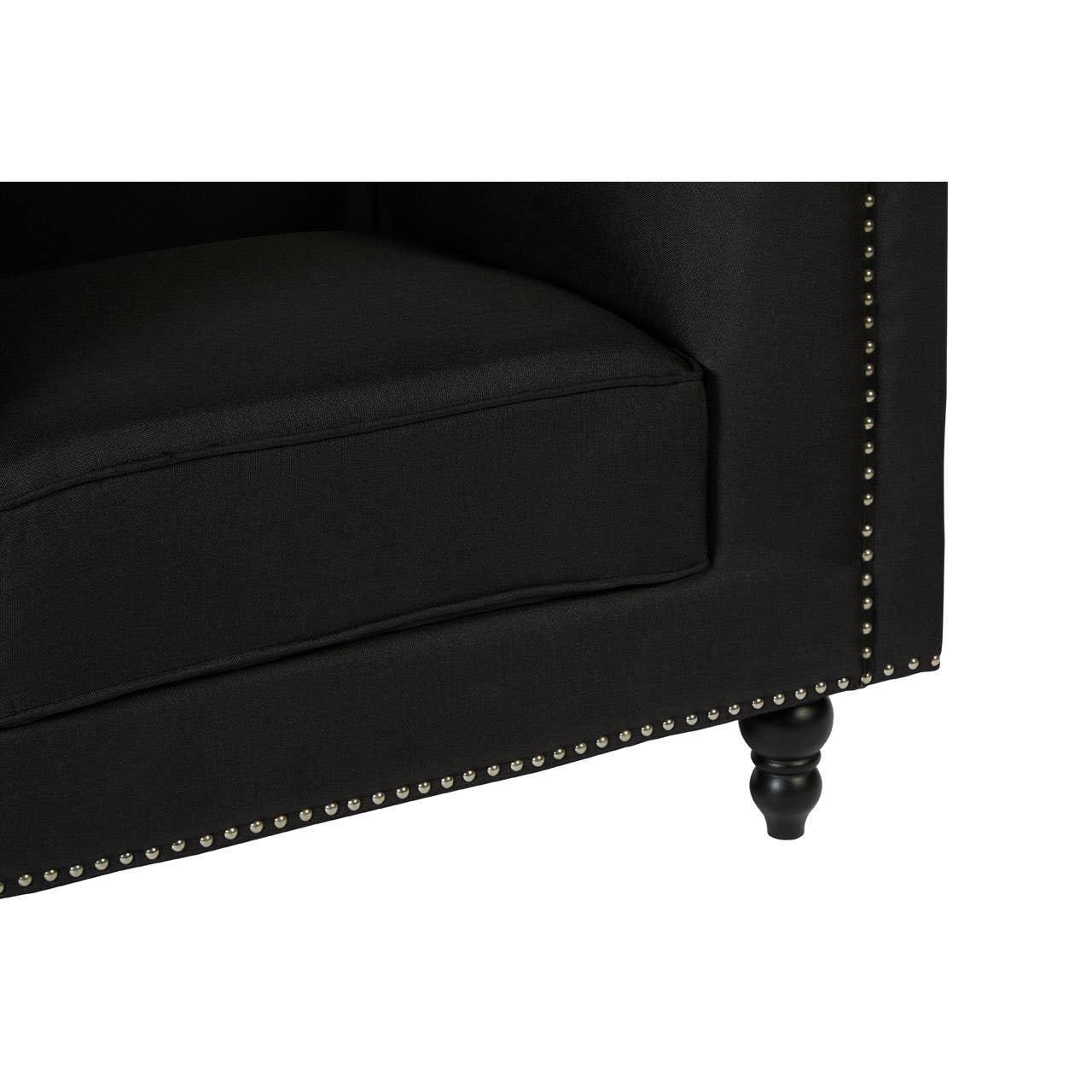 Black fabric sofa corner with studded trim and turned wooden leg close-up